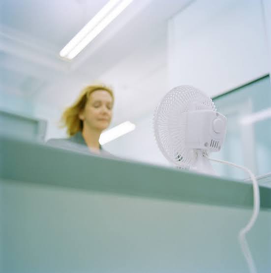 Woman sitting at the desk with a fan on