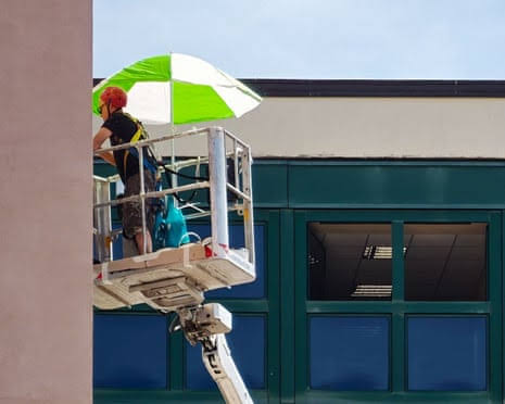 Man working in the sun with an umbrella for protection