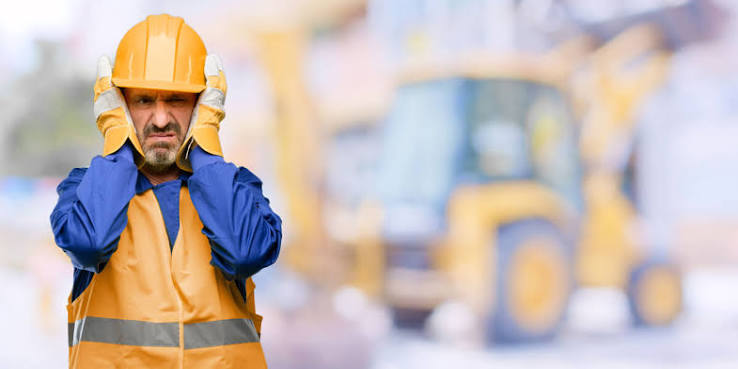 Man covering ears with hands in a noisy environment