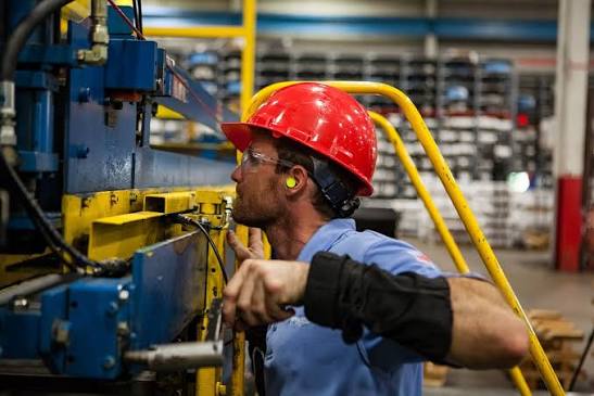Man working with noisy machinery wearing ear plugs